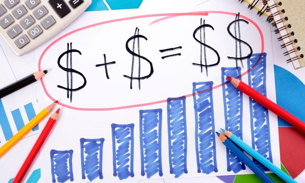 Hand-drawn math equation showing dollar signs adding up to a larger result, surrounded by hand-drawn bar charts, colored pencils, and a calculator