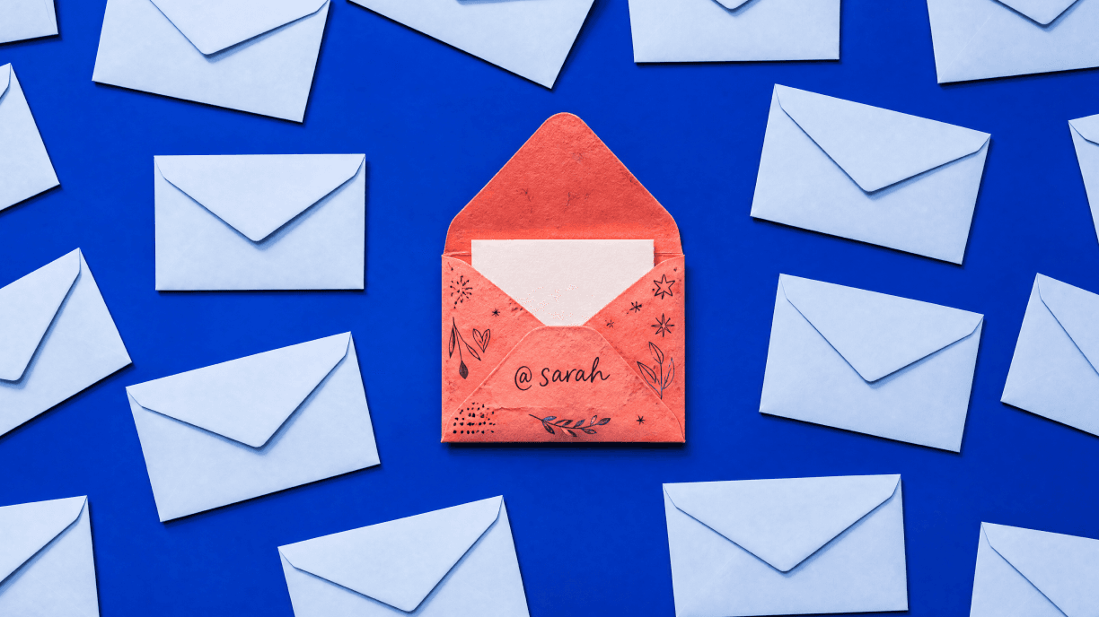 Coral envelope addressed to Sarah surrounded by white envelopes on a blue background.